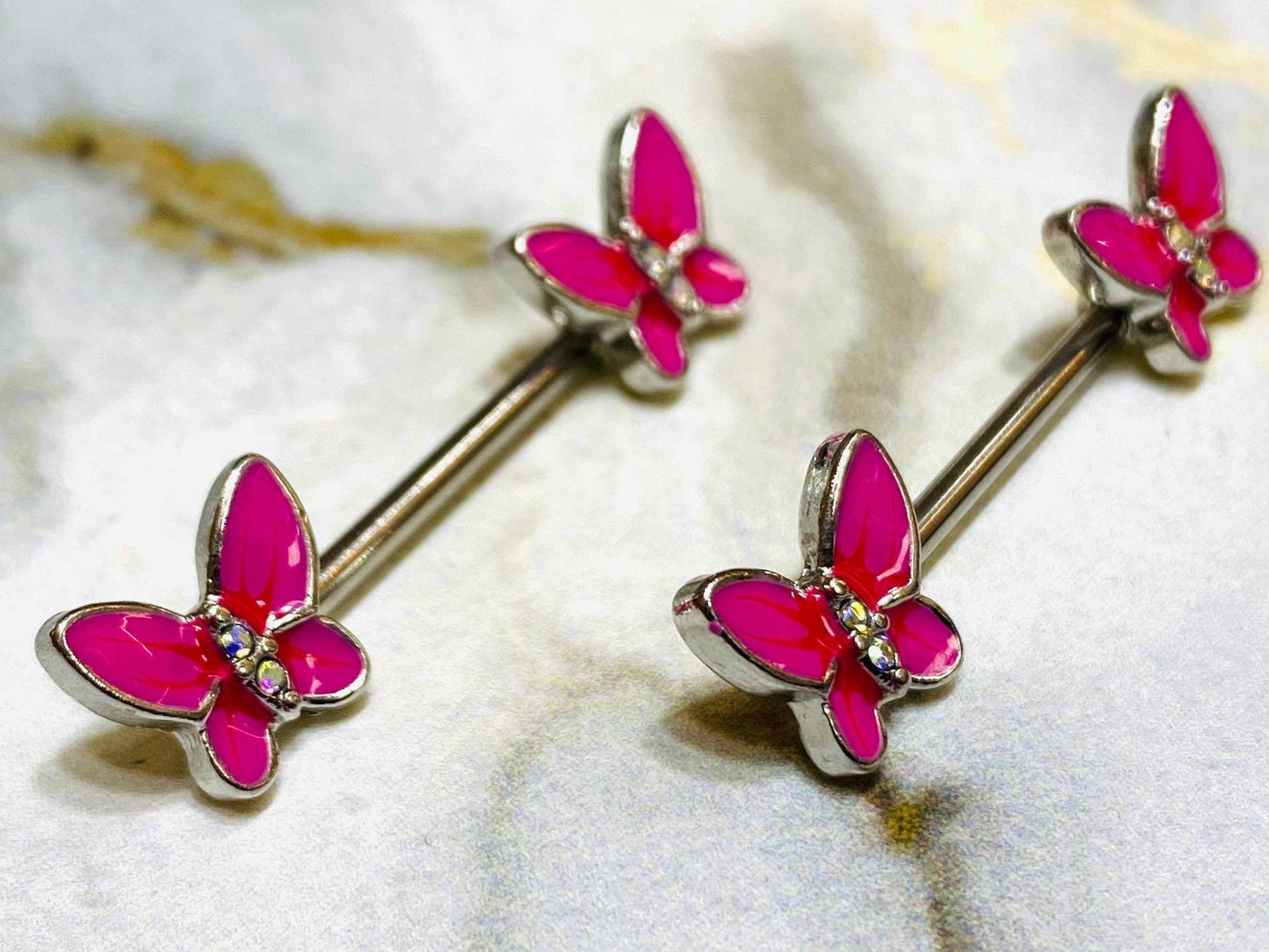 A pair of 14G Pink Butterly Ends Nipple Barbells. Nipple Jewelry. Nipple Piercing. Nipple Rings.